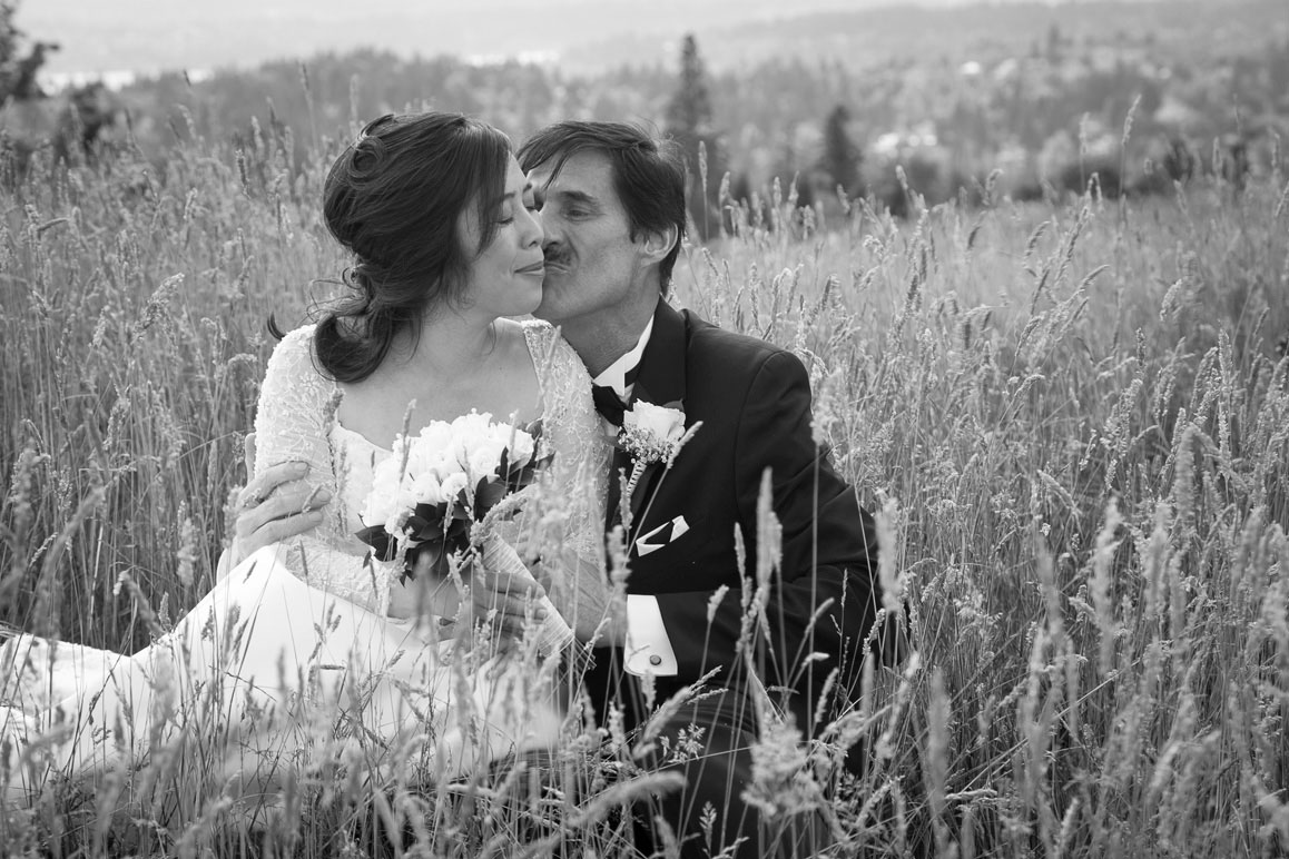 Wedding at Newcastle Golf Club Bride and groom sitting and kissing in the tall grass at Newcastle Golf Club