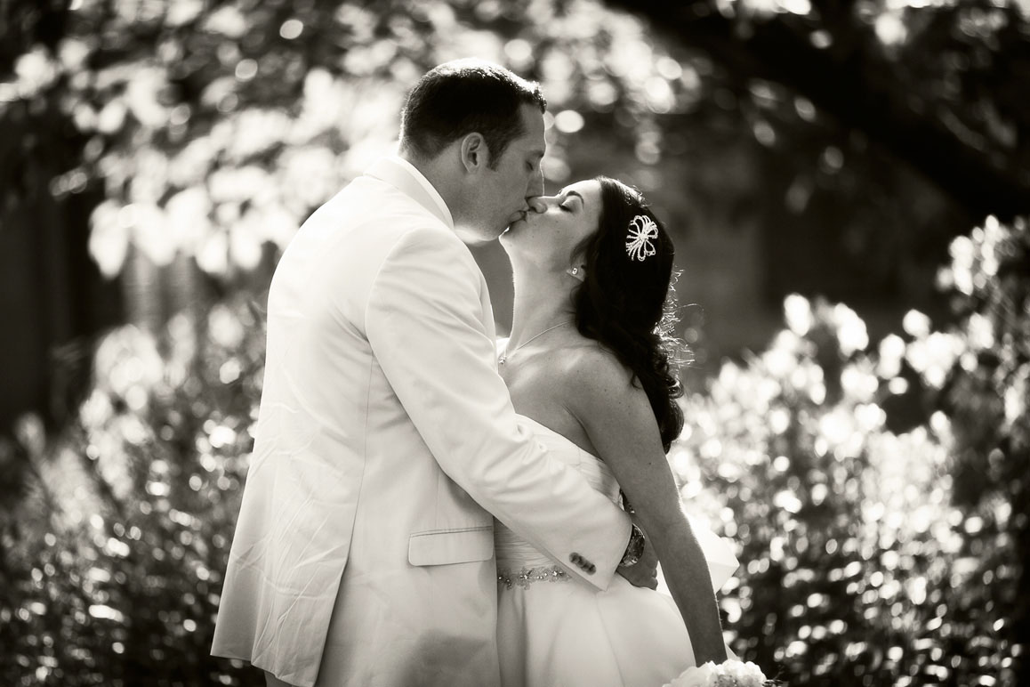 Jenn & Larry - Seattle wedding at Ray's Boathouse Backlit photo of couple kissing with flowers in background