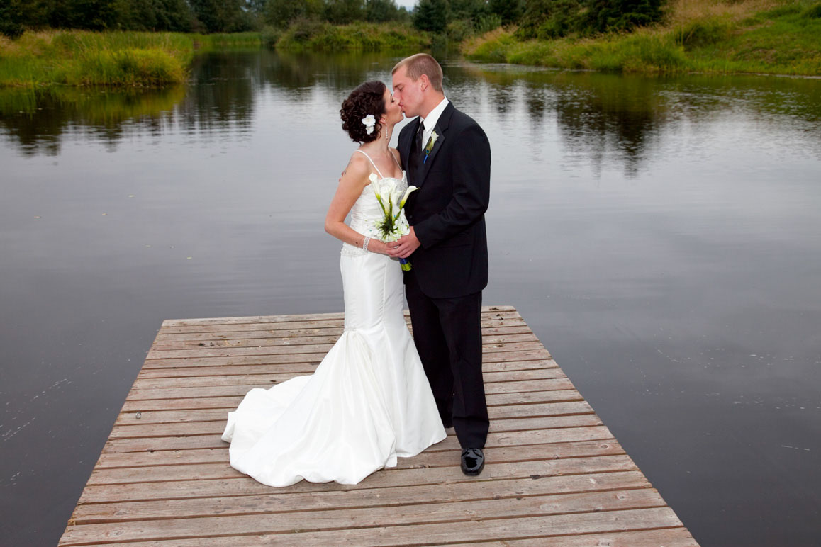 Wedding at Lord HIll Farm Bride and groom standing on dock and kissing at Lord Hill Farm in Monroe